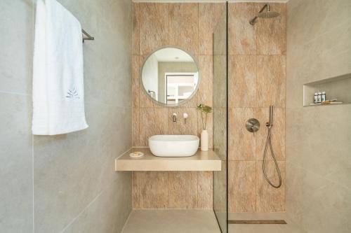 a bathroom with a shower with a sink and a mirror at Aspronissos Hotel in Skiathos