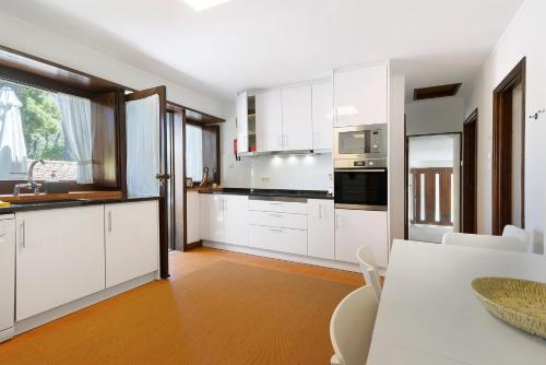 a white kitchen with white cabinets and a table at Casa de Santo António Moledo in Moledo