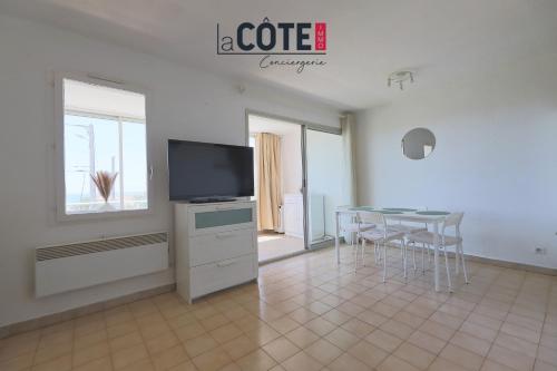 - un salon avec une table, une télévision, une table et des chaises dans l'établissement Le baoucailla, à Martigues