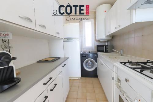 une cuisine blanche avec un lave-linge et un sèche-linge. dans l'établissement Le baoucailla, à Martigues