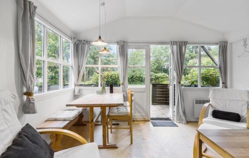 a dining room with a table and some windows at Nice Home In Nexø With Kitchen in Neksø