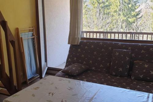 a couch in a room with a large window at Duplex lumineux et spacieux en plein centre bourg in Saint-Pierre-de-Chartreuse