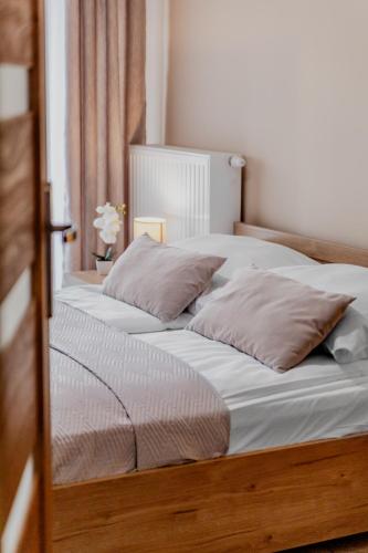 a bed with two pillows on it in a bedroom at Apartamenty Cicha - bezpłatny parking in Krynica Zdrój