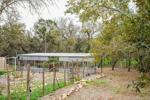 a building with a fence in a field with trees at Spacious Resort with 2 Cabins on 3 Acres in Driftwood