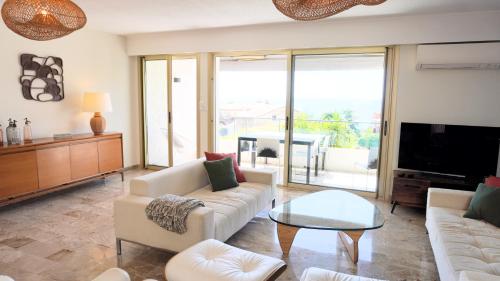 a living room with a couch and a table at Villa avec Rooftop, Jacuzzi & vue mer by Palmazur in Mandelieu-la-Napoule