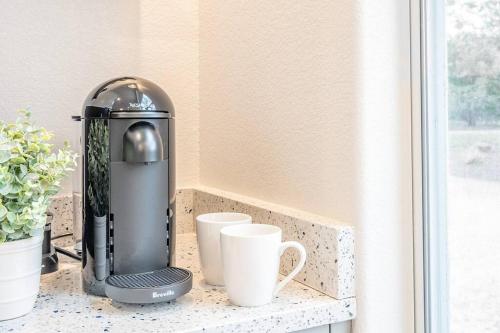 a coffee machine sitting on a counter next to cups at Spacious Resort with 2 Cabins on 3 Acres in Driftwood