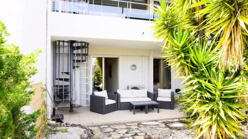 a patio with black furniture and palm trees at Villa avec Rooftop, Jacuzzi & vue mer by Palmazur in Mandelieu-la-Napoule