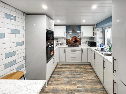 a kitchen with white cabinets and a wooden floor at The Blue House in Portrush
