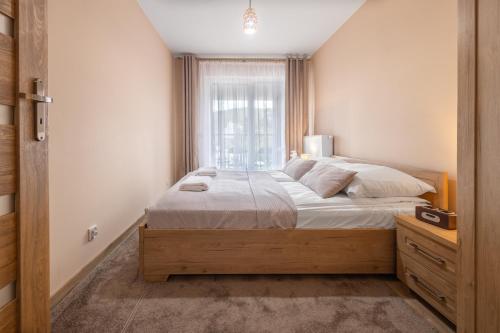 a bedroom with a large bed and a window at Apartamenty Cicha - bezpłatny parking in Krynica Zdrój