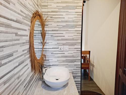 a bathroom with a toilet and a mirror on a wall at The New Blue Waves Hotel in Jambiani