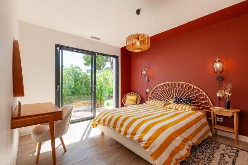 - une chambre avec des murs rouges, un lit et un bureau dans l'établissement Villa avec piscine à Marseille, à Marseille