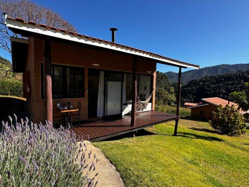 a house with a wooden deck in the grass at 4 Estações & Chalé da Pedra in Sapucaí-Mirim