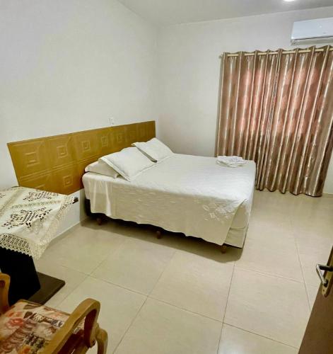 a bedroom with a white bed and a window at Hotel Ametista in Ametista do Sul