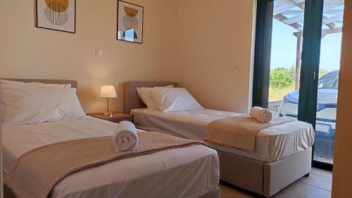Una habitación de hotel con dos camas y balcón. en Villa MINIMA, en Asprouliánoi