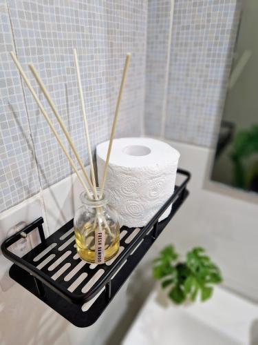 a black shelf with a roll of toilet paper and a jar with bamboo sticks at Bahay ni Asik - Homestay near SM City in Davao City