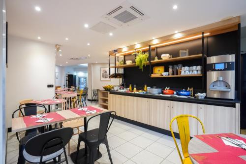 a restaurant with tables and chairs and a kitchen at Campanile Paris 14 - Maine Montparnasse in Paris