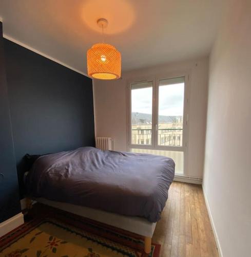 une chambre avec un lit et une grande fenêtre dans l'établissement Appartement cosy - Le Verdun, à Caen
