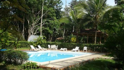 a swimming pool with white chairs and a table and chairs at Albergue de Montaña Talari in San Isidro
