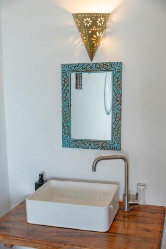 a bathroom with a white sink and a mirror at Mnana Beach Bungalows in Michamvi