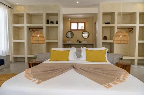 a bedroom with a large white bed with yellow pillows at Mnana Beach Bungalows in Michamvi