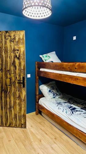 une chambre bleue avec un lit superposé et une porte ouverte dans l'établissement La Maison des Sortilèges, à Perpignan