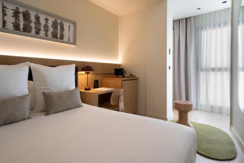 a bedroom with a large white bed and a desk at Ocean Drive Sevilla in Seville