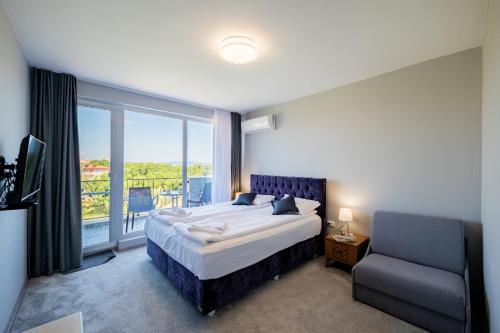 a bedroom with a bed and a window and a chair at La Mansión in Lozenets