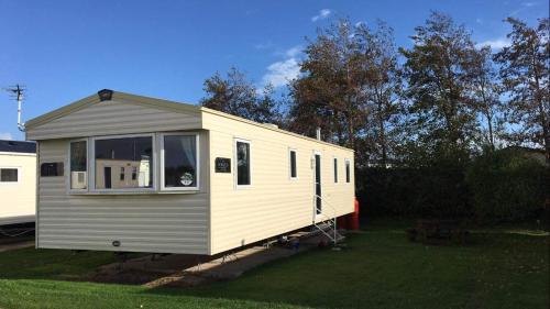 a white and gray tiny house in a yard at Haven Church Farm in Pagham