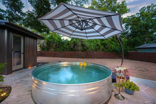 an umbrella sitting over a pool in a backyard at Cava House, Hot tub, Cowboy Pool, Fire pit! in Fredericksburg