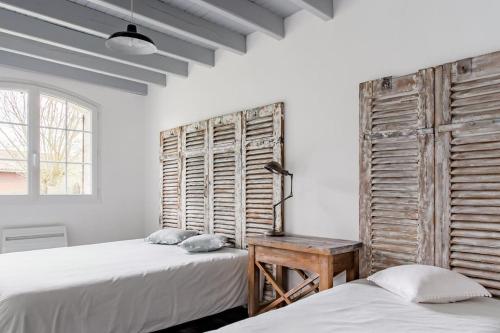 two beds in a room with white walls and a window at Gite Gauriaguet in Gauriaguet