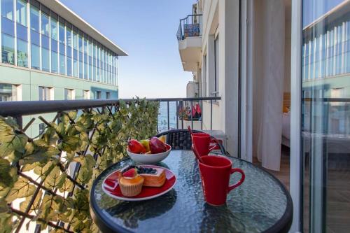 - une table avec un bol de fruits et des petits gâteaux sur le balcon dans l'établissement ApartHotel Riviera - Balcon Lenval Sea View with AC Promenade des Anglais, à Nice