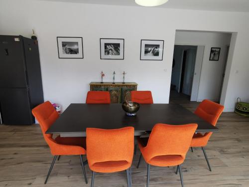 une salle à manger avec une table noire et des chaises orange dans l'établissement Fleurs, à Bassussarry