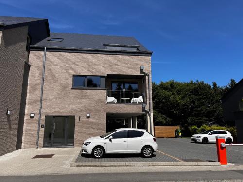 a white car parked in front of a brick building at Appartement de charme in Vaux-sur-Sûre