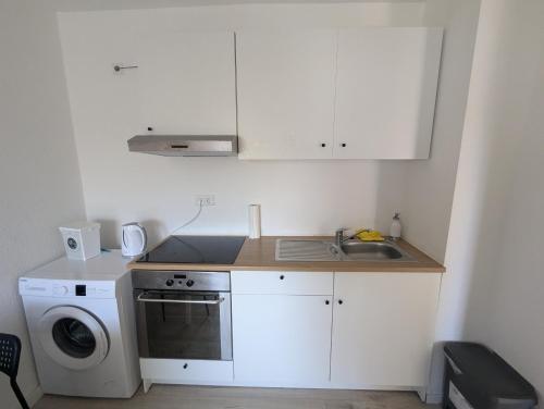uma cozinha com pia e máquina de lavar em Wohnung am Fischereihafen Modern & gemütlich em Bremerhaven
