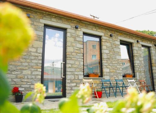 a brick building with windows and chairs in front of it at Gogo Moustache Guest House in Përmet