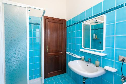 ein blaues Badezimmer mit Waschbecken und Spiegel in der Unterkunft Sea View - Cozy apartment with parking space in San Teodoro