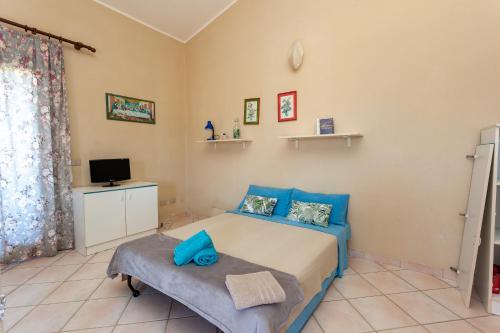 ein Schlafzimmer mit einem blauen Bett und einem Fernseher in der Unterkunft Sea View - Cozy apartment with parking space in San Teodoro