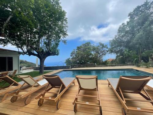a group of chairs sitting next to a swimming pool at Villa prestige avec piscine - dans les hauteurs de Bastia in Bastia