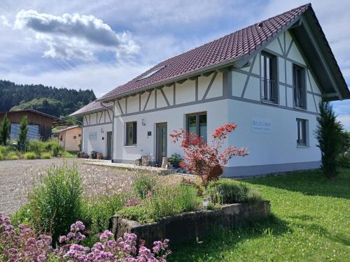 a white house with a garden in front of it at Binzighof Ferienhäuser in Oberkirch