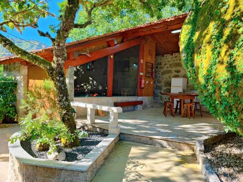 a wooden house with a table and a tree at Casa do Penedo in Castro Laboreiro