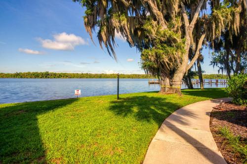 a tree and a sidewalk next to a lake at Pool Access and Lanai Riverfront Welaka Condo! in Georgetown