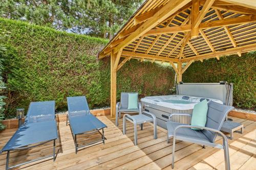 a patio with a grill and chairs and a wooden deck at Domaine du Gros Chêne - terrasses avec jacuzzis privatifs in Ablon