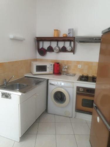 une cuisine avec un lave-linge et un micro-ondes dans l'établissement Appartement près des plages en plein centre ville, à Loupian