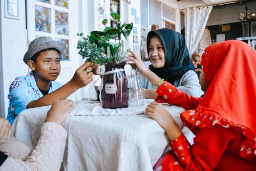 a group of people sitting around a table with a vase at Imah Seuri by Kaya Rooms in Tutugan