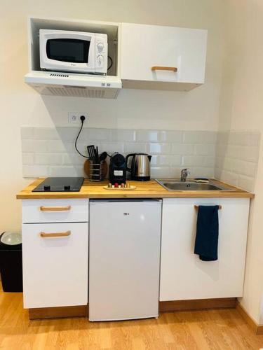 une cuisine avec des placards blancs et un four micro-ondes sur un comptoir dans l'établissement Studio Charles de Gaulle II, à Castres