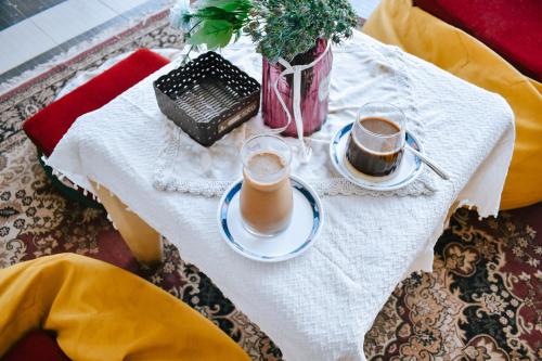 a table with two glasses of coffee and a vase at Imah Seuri by Kaya Rooms in Tutugan