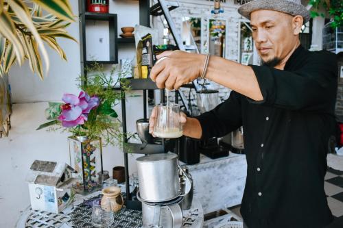 a man is making a drink in a blender at Imah Seuri by Kaya Rooms in Tutugan
