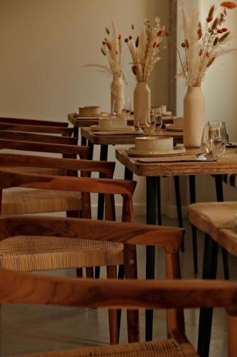 a row of wooden tables and chairs with vases at La Maison Gaïa Hôtel & Spa in Torreilles