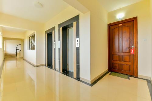 a hallway with a wooden door in a building at Super Hotel O Tyche Stays in Trivandrum