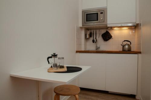 eine Küche mit weißen Schränken und einer weißen Arbeitsplatte in der Unterkunft Cosy one bedroom close to Paris & Stade de France in Saint-Denis
